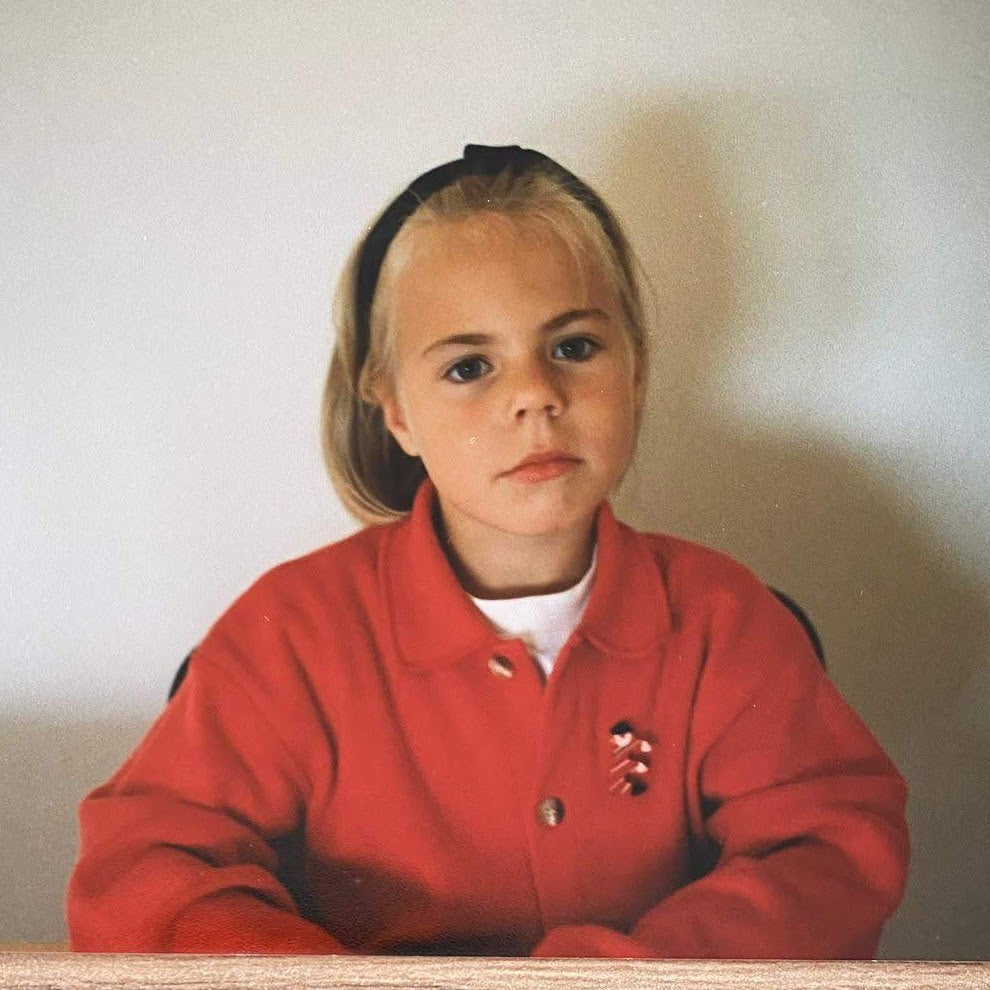 Young girl wearing a red jacket with a white background
