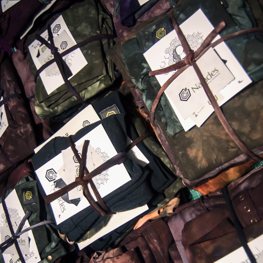 Collection of folded clothing stacks in earthy coors with visible branding on a textured surface